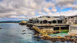 A waterfront hotel with multiple buildings extending over the water, connected by walkways. - Holiday Inn Express at Monterey Bay by IHG (Seaside)