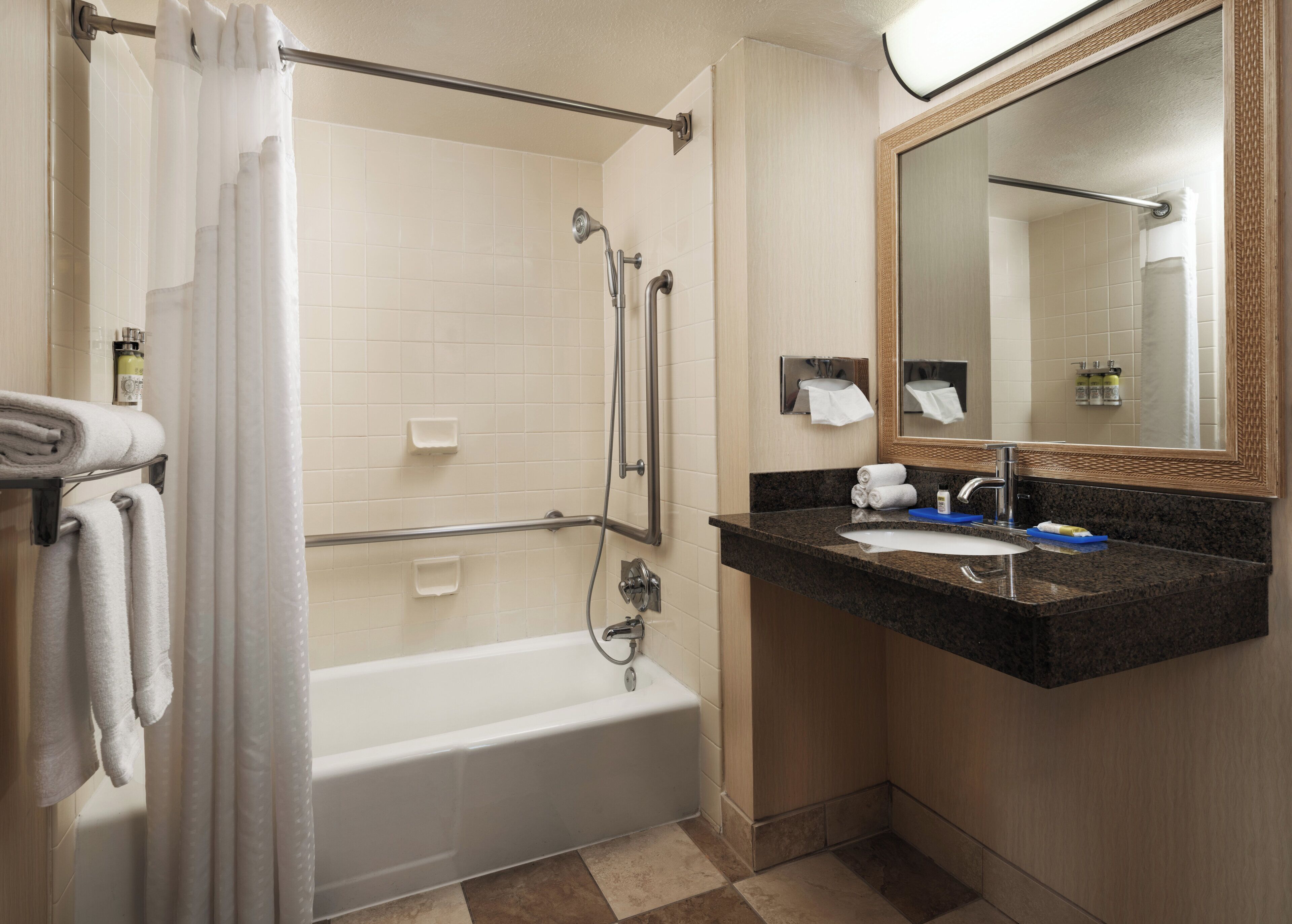 A bathroom with a bathtub, a sink, a mirror, and a shower curtain.