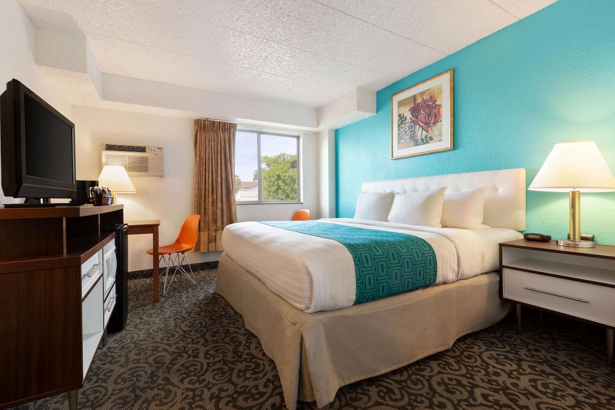A hotel room with a bed, a desk, a television, and a chair.