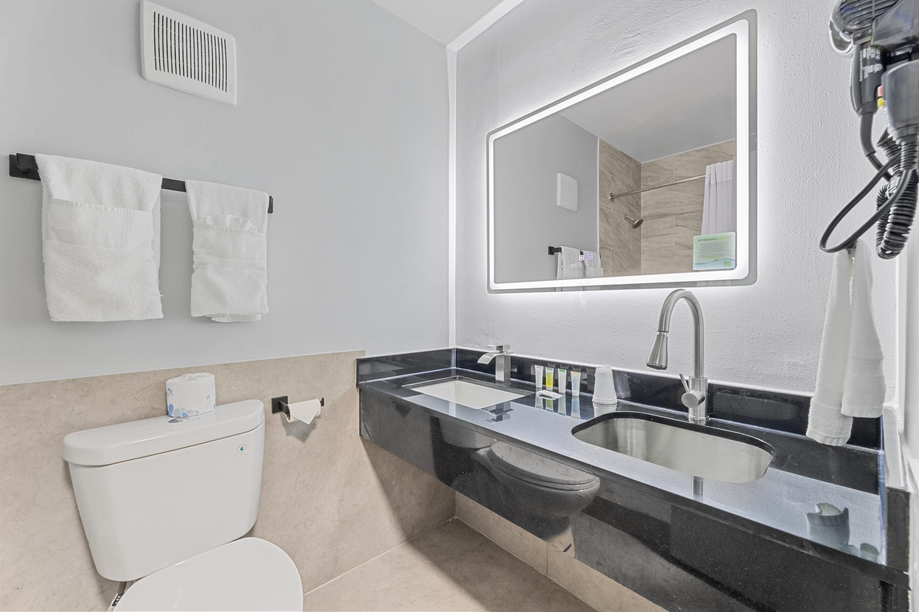 A modern bathroom with a toilet, sink, and mirror.