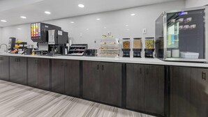 Una estación de café moderna con varias máquinas de café, un refrigerador con exhibición y diferentes cápsulas y recipientes para café.