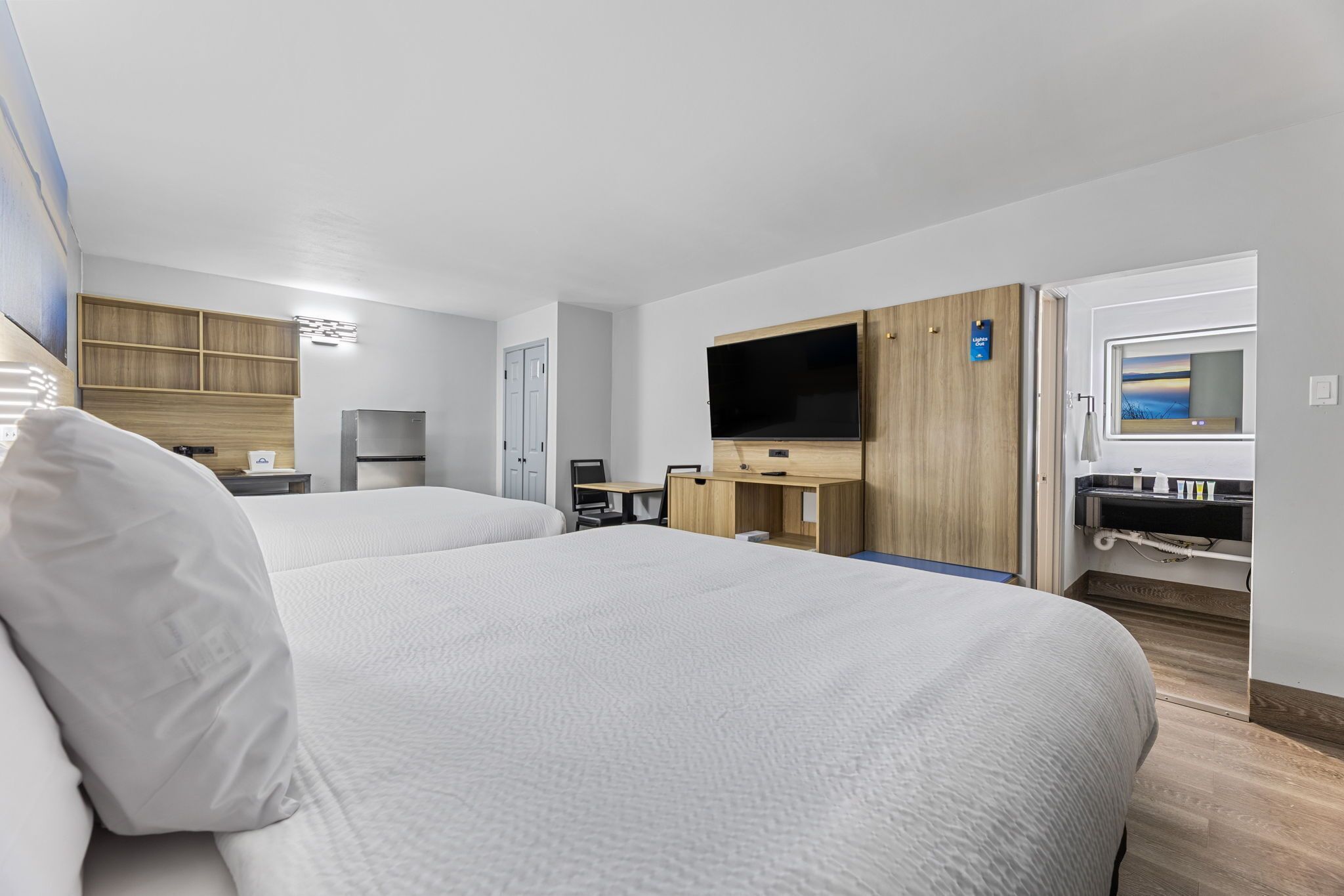 A hotel room with two beds, a TV, a desk, and a wardrobe.