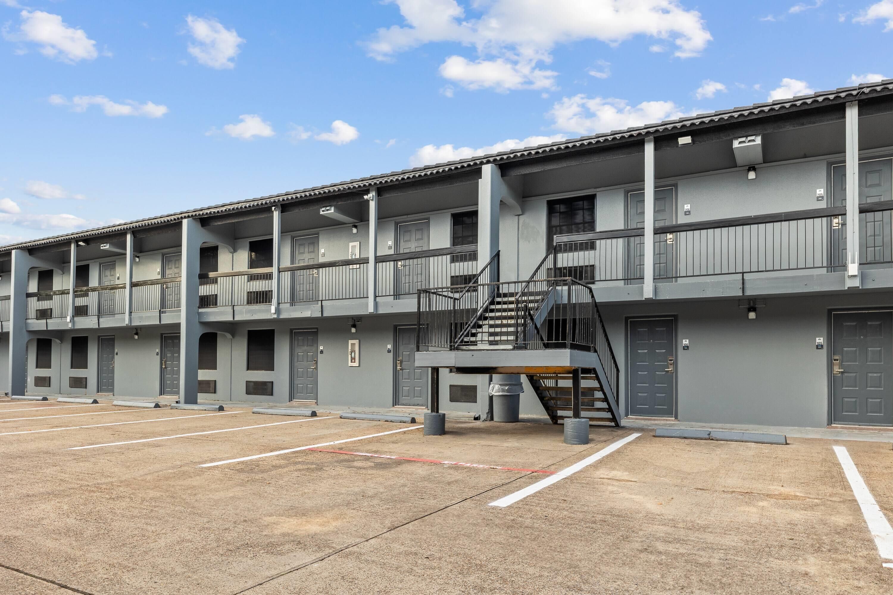 A multi-story motel with a central staircase, multiple balconies, and a parking lot.