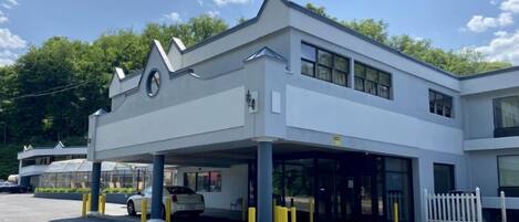 A modern building with a covered parking area and a white fence.