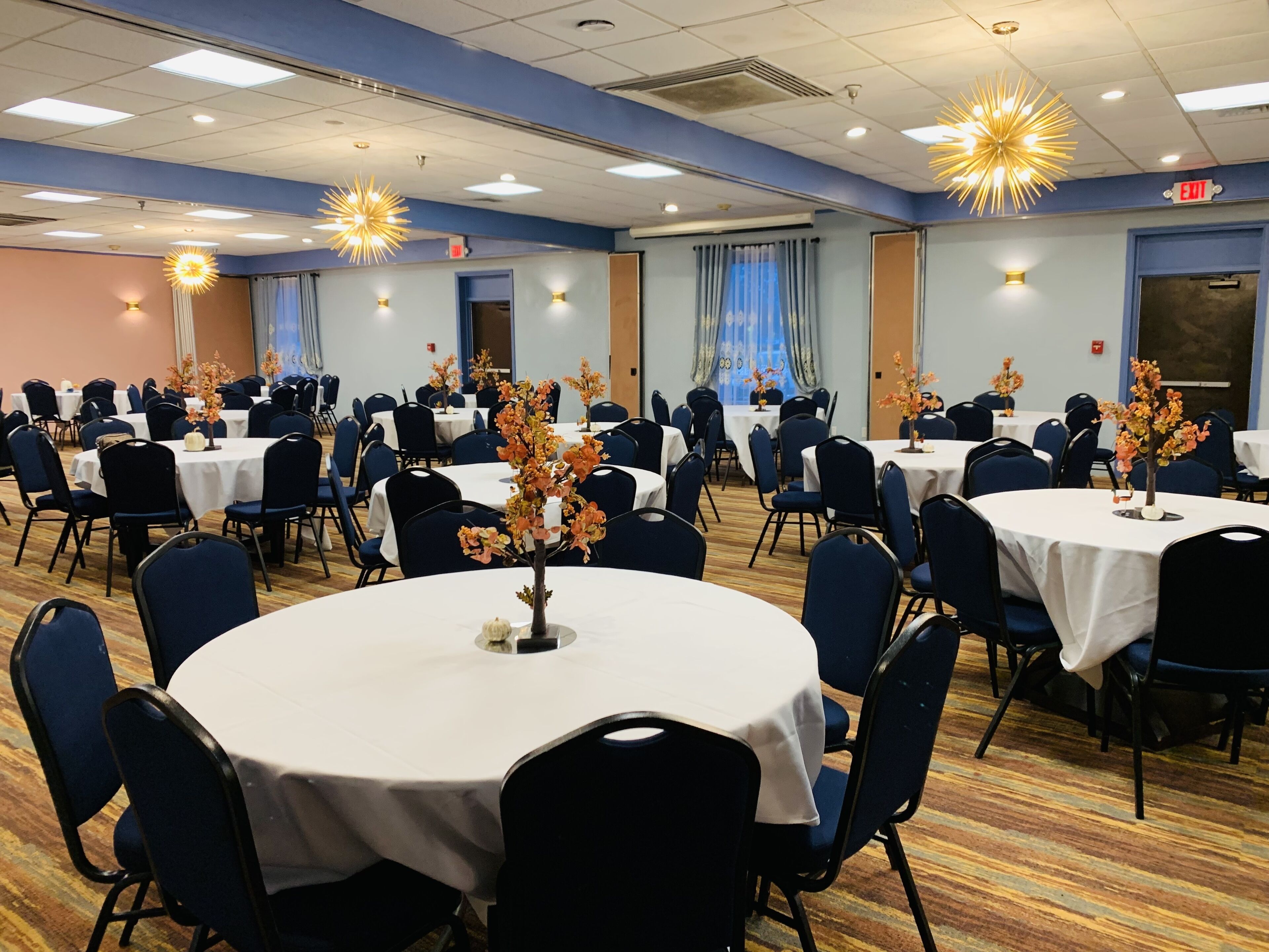 A conference room with round tables, blue chairs, and floral centerpieces.