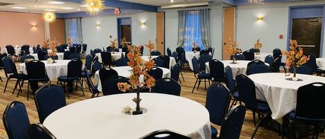 A conference room with round tables, blue chairs, and floral centerpieces.