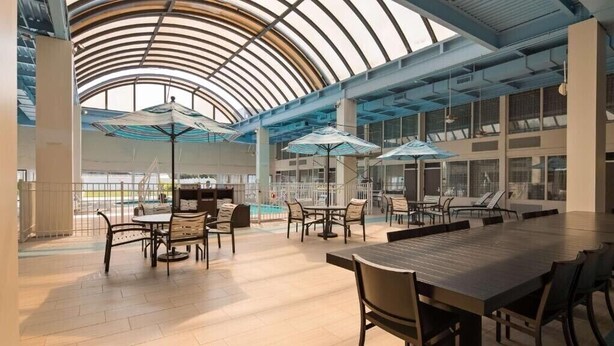 A spacious indoor area with a high ceiling, large windows, and a pool area.