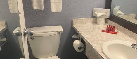 A bathroom with two toilets, a sink, a mirror, and a towel rack with towels.