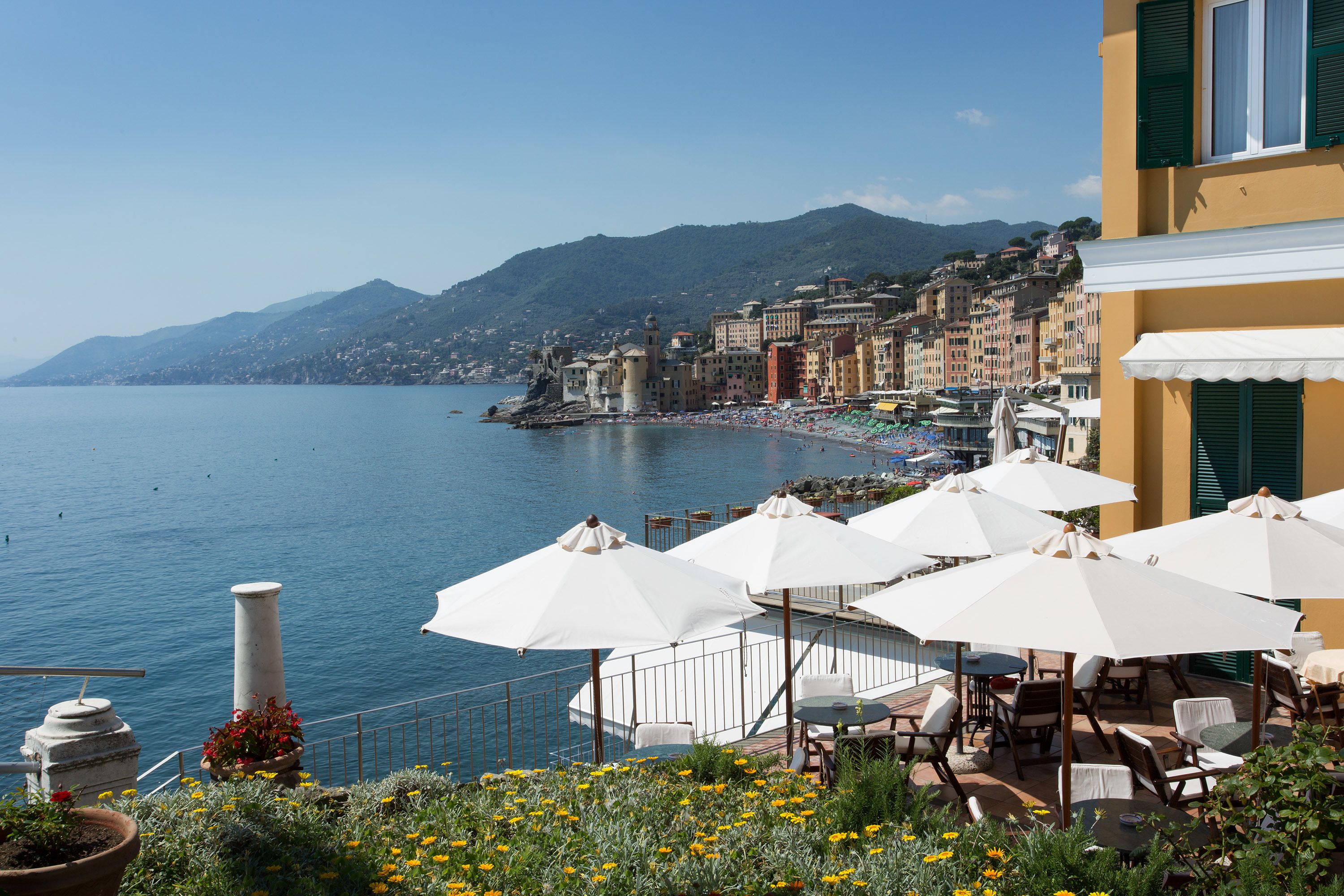 Une terrasse en bord de mer, dotée d’un espace extérieur aménagé et offrant une vue sur la mer et les bâtiments.