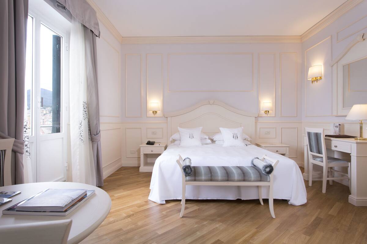 Une chambre d’hôtel avec un grand lit, des tables de chevet, un bureau et une chaise.