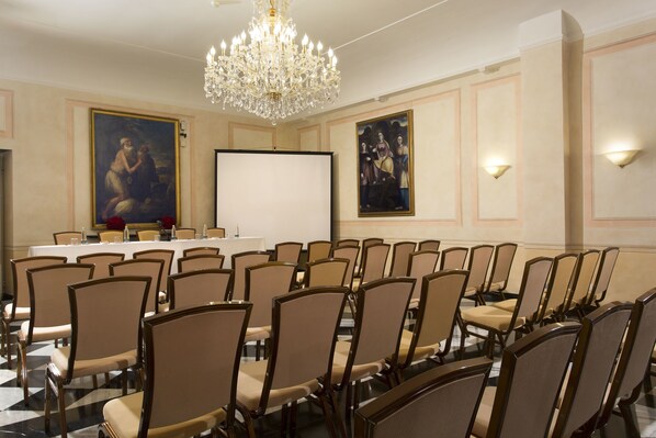 A conference room with a long table, multiple chairs, a projector screen, and two large paintings on the walls. - Hotel Cenobio Dei Dogi (Camogli)