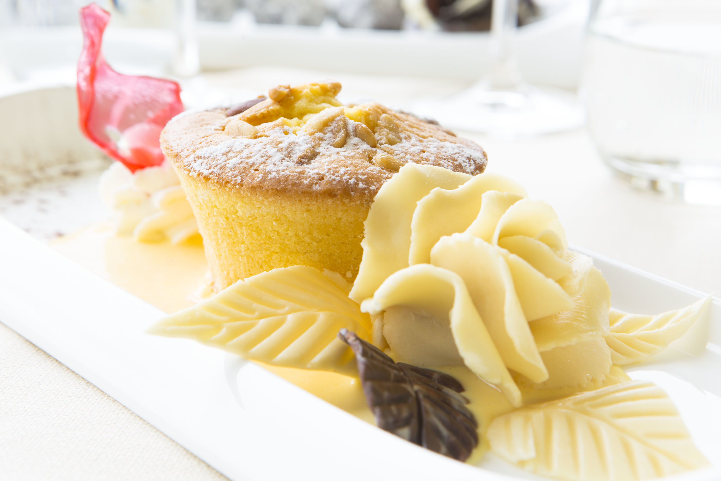 Un plato de postre con un muffin, crema batida y una decoración de hoja de chocolate.