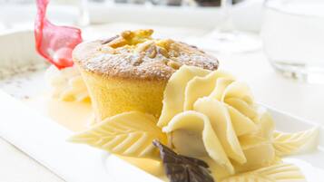 Un plato de postre con un muffin, crema batida y una decoración de hoja de chocolate.