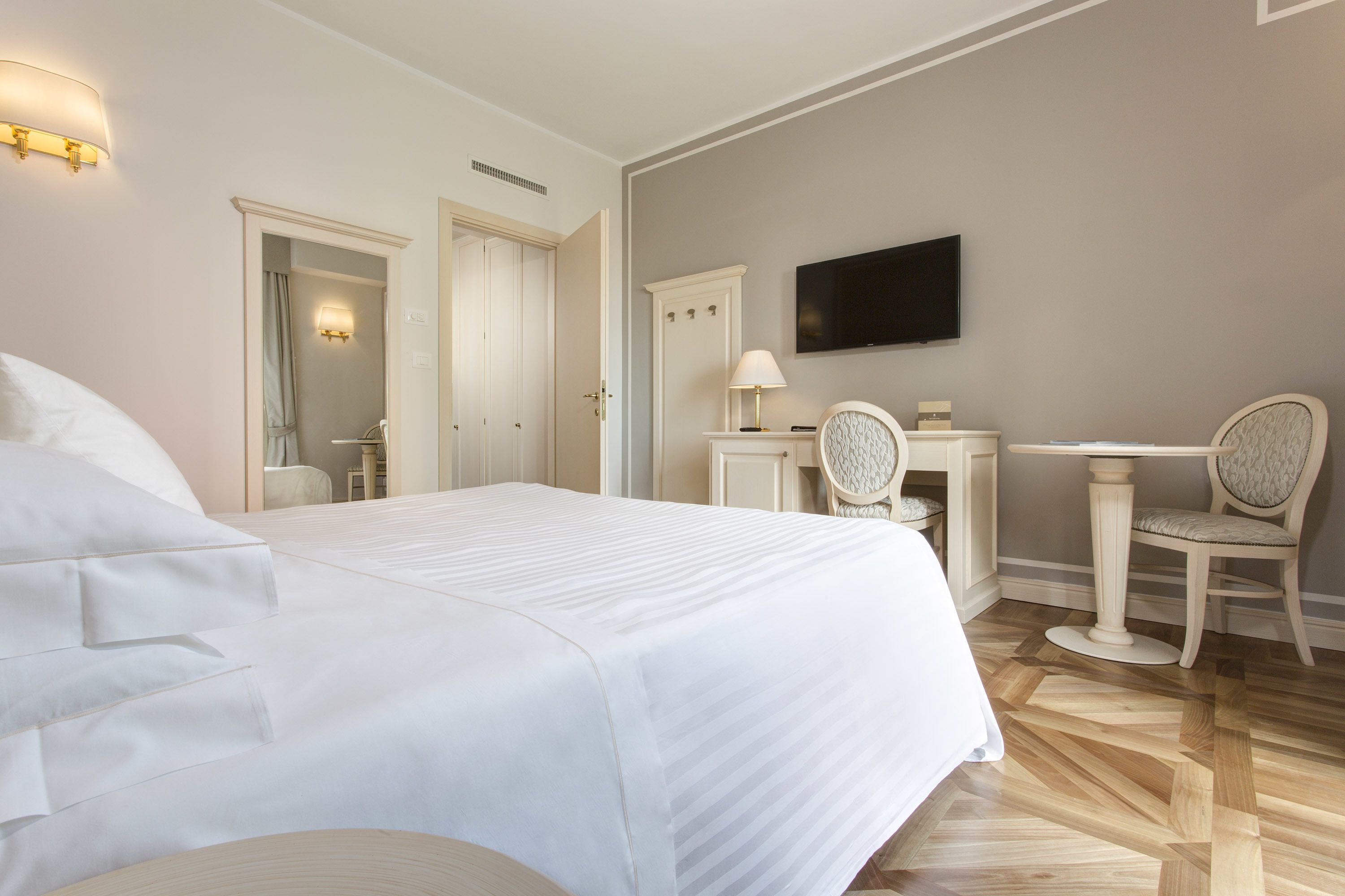 Ein Hotelzimmer mit einem großen Bett, einem Schreibtisch mit Stuhl, einem Fernseher und einem Spiegel.