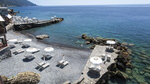 A seaside terrace with sun loungers and umbrellas, overlooking clear blue waters and a rocky shoreline. - Hotel Cenobio Dei Dogi (Camogli)
