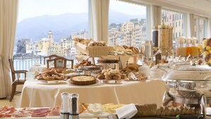 A buffet table with various food items and a view of a coastal city. - Hotel Cenobio Dei Dogi (Camogli)