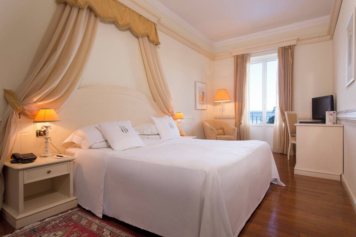 Une chambre d’hôtel avec un grand lit, des lampes de chevet, un bureau et une télévision.