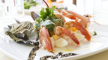 Un plat de fruits de mer composé de crevettes, d’huîtres et de légumes verts, servi dans une assiette blanche.