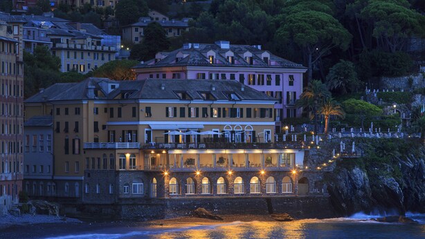 A coastal hotel with multiple balconies overlooking the sea, a stone facade, and a view of the surrounding hillside. - Hotel Cenobio Dei Dogi (Camogli)
