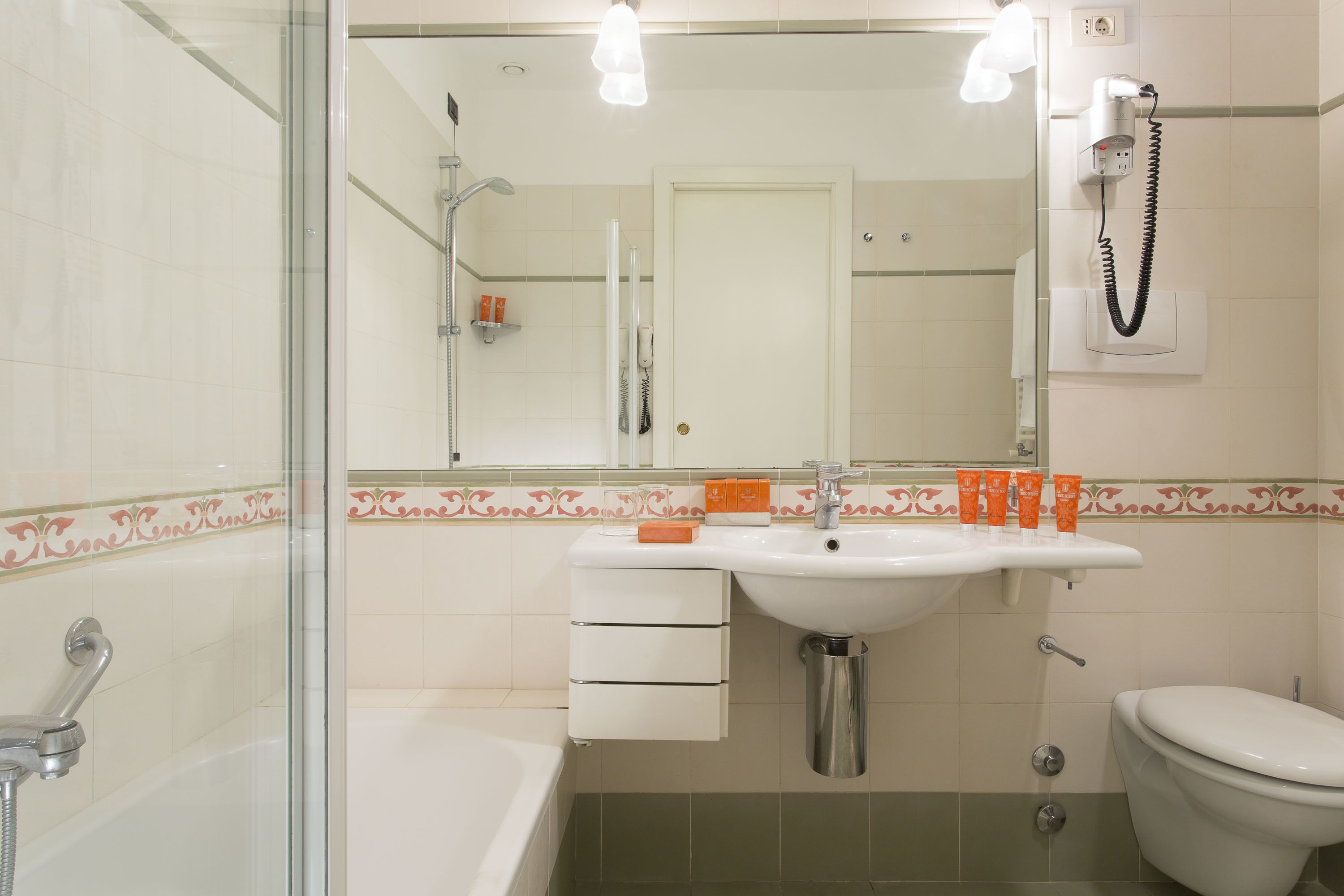 Un baño con ducha envuelta en vidrio, un lavabo blanco con espejo y un inodoro.