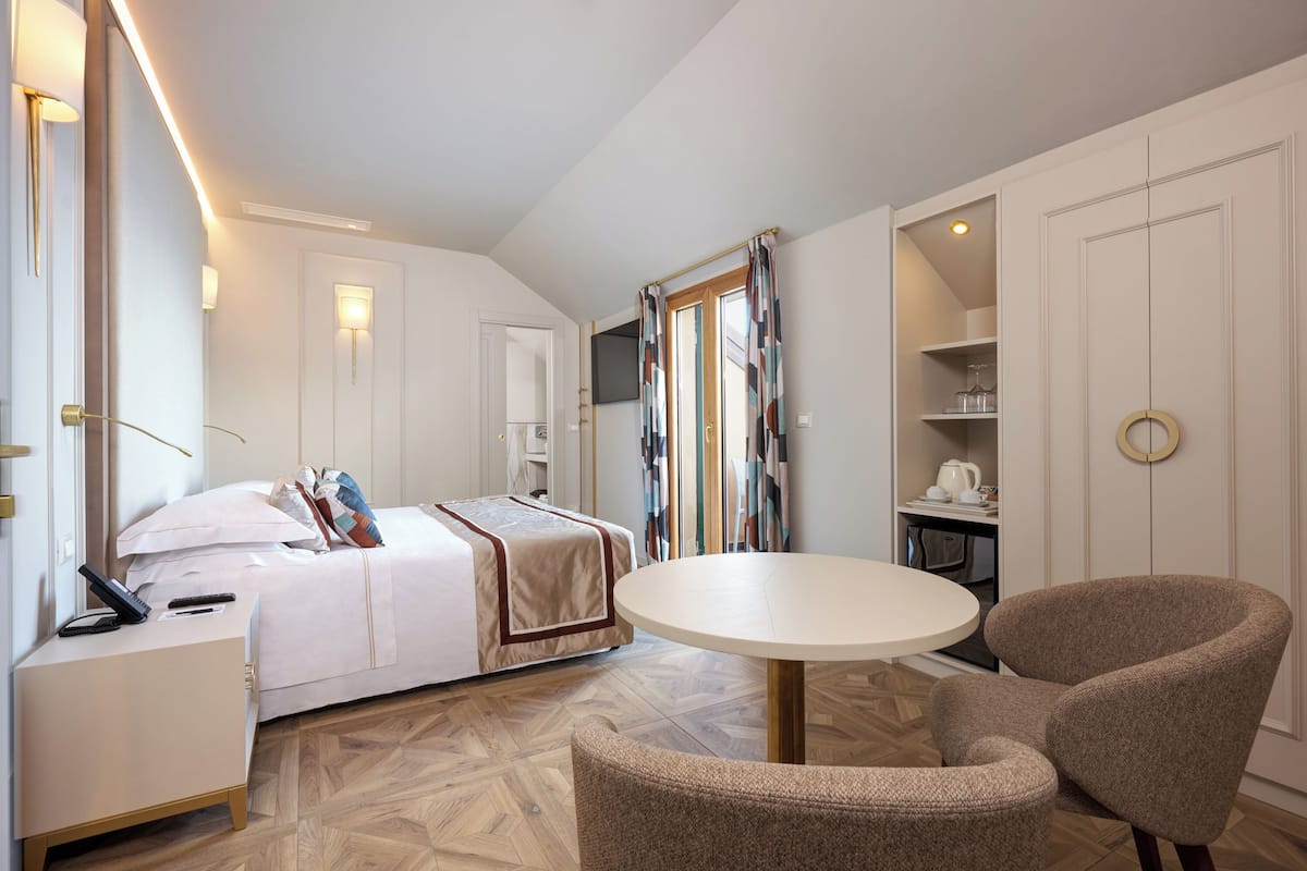 Une chambre d’hôtel comprenant un lit, une table de chevet, une chaise, une table ronde et une armoire.