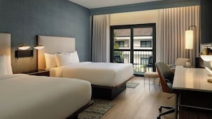 A hotel room with two beds, a desk, a chair, and a balcony with curtains. - Courtyard by Marriott Orlando Airport (Orlando)