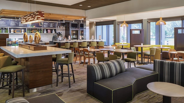 A modern restaurant with a bar area, seating arrangements, and a visible menu board. - Courtyard by Marriott Orlando Airport (Orlando)