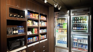 A kitchenette with a microwave, storage cabinets, and two beverage dispensers. - Courtyard by Marriott Orlando Airport (Orlando)