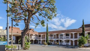A multi-story building with a courtyard, a sign for a value pool parking station, and a DEWAY INN sign. - Rodeway Inn Magic Mountain Area (Castaic)