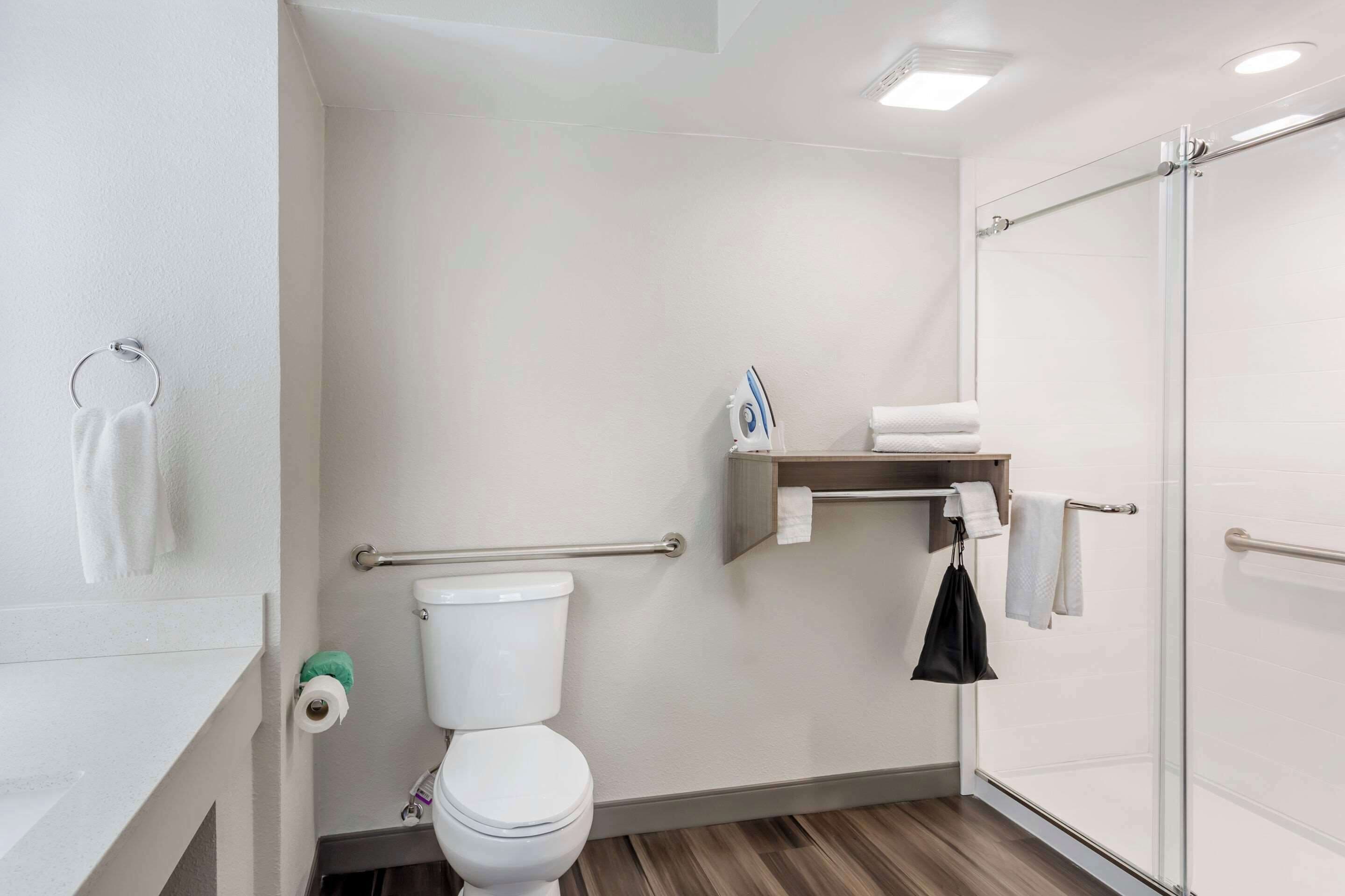 Une salle de bain moderne équipée de toilettes, d’une douche et d’un porte-serviettes.