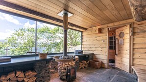 A cozy cabin with a stone fireplace, a large window, and a wooden interior. - Low Wood Bay Resort & Spa (Windermere)
