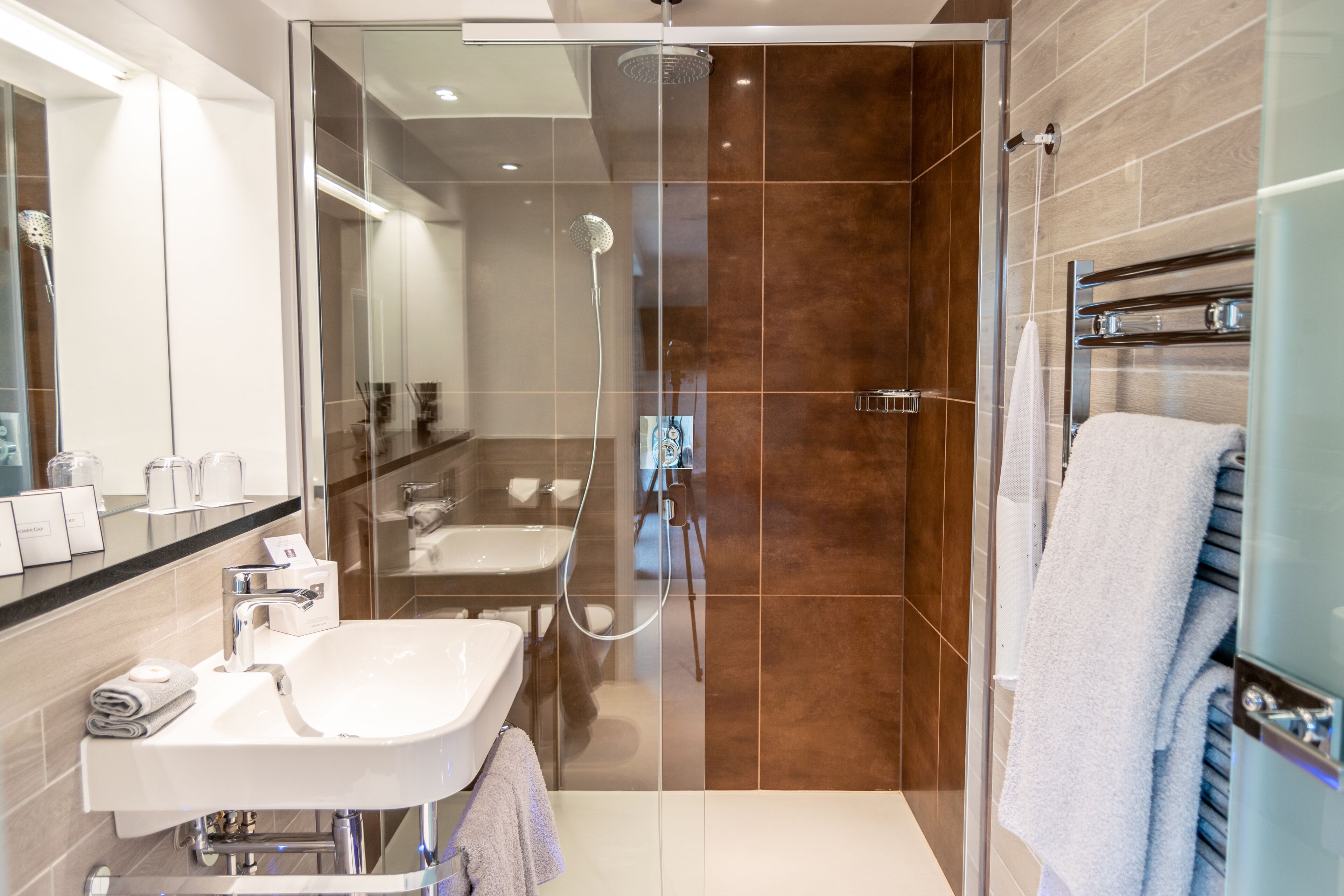 A modern bathroom with a glass-enclosed shower, a white sink, and a towel rack.