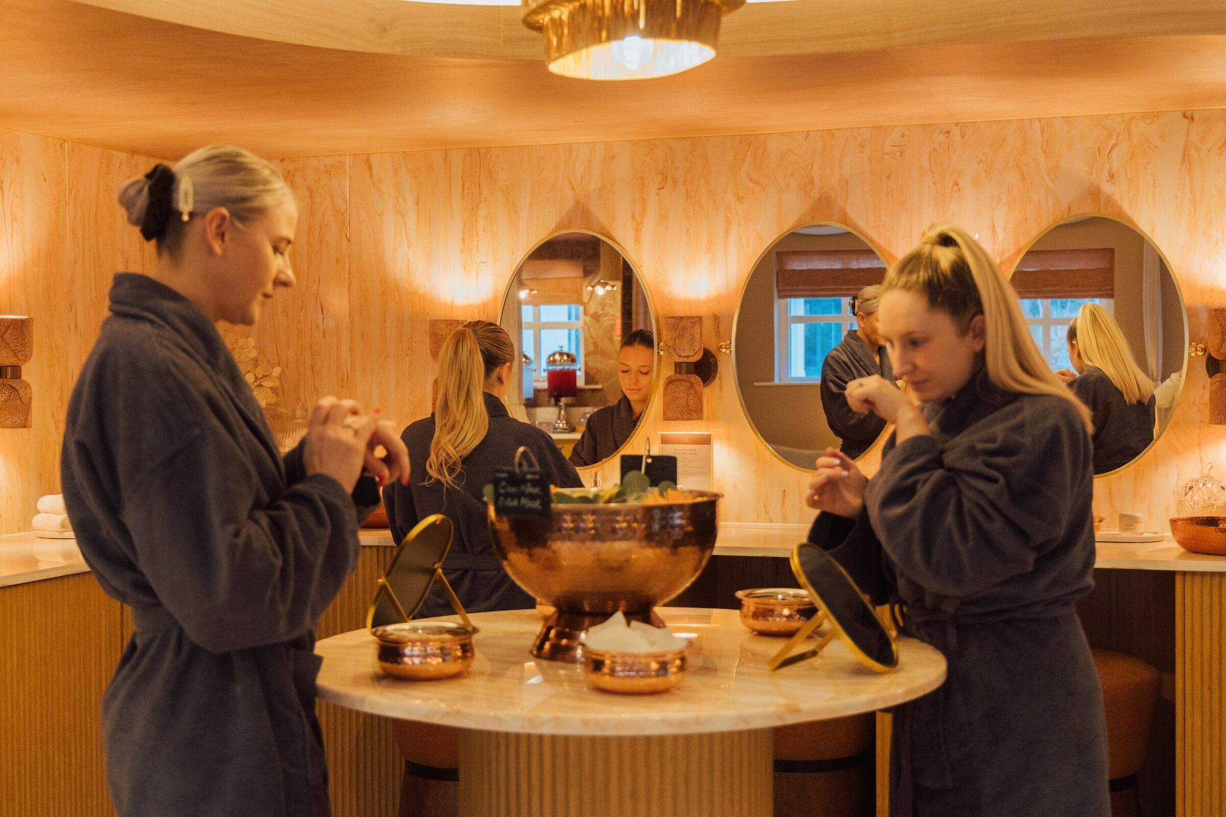 A spa setting with a central round table, multiple mirrors, and a wooden interior.
