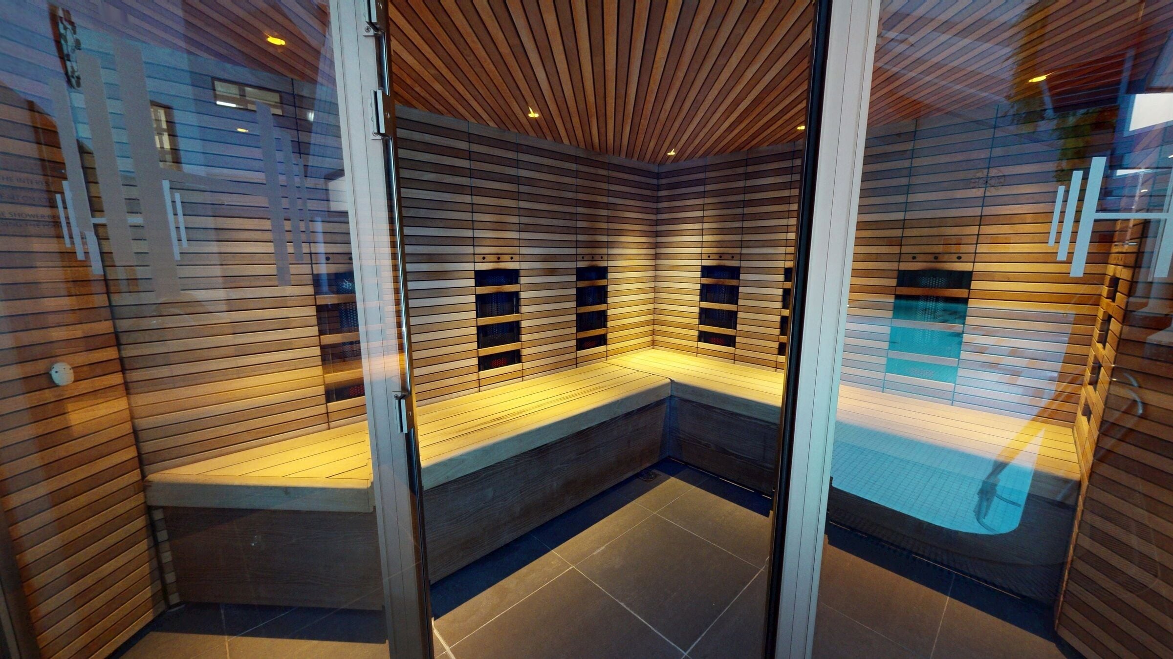 A sauna with wooden slats, a bench, and a tiled floor.