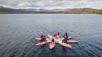 A group of people on paddleboards in a calm lake with mountains in the background.