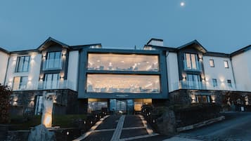 A modern building with a large glass facade, a stone base, and a well-lit entrance.