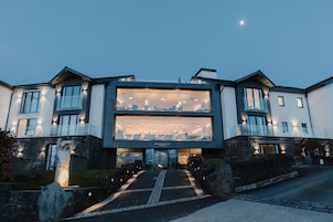 A modern building with a large glass facade, a stone base, and a well-lit entrance.