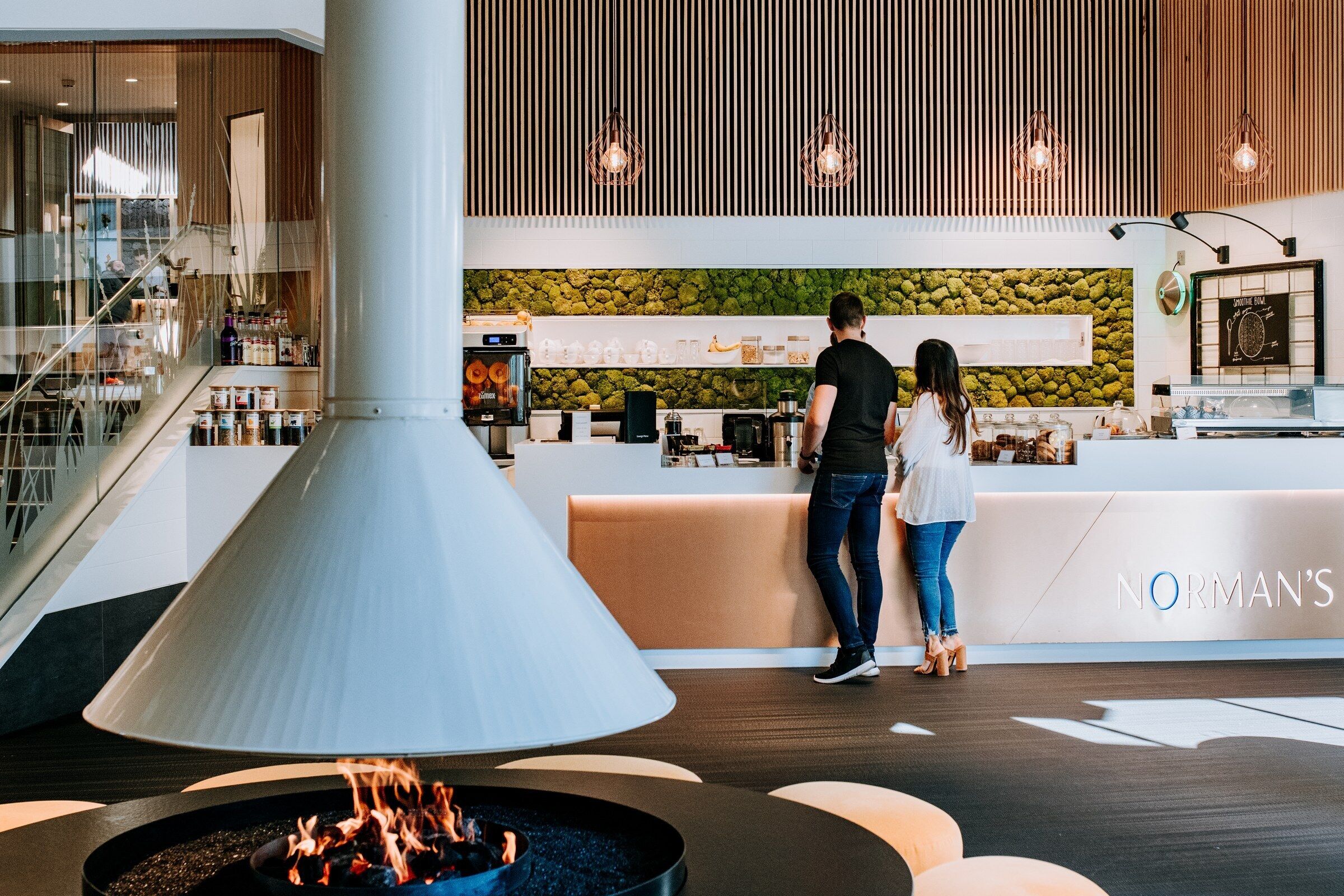 A modern interior with a central fire feature, a reception desk, and a bar area.