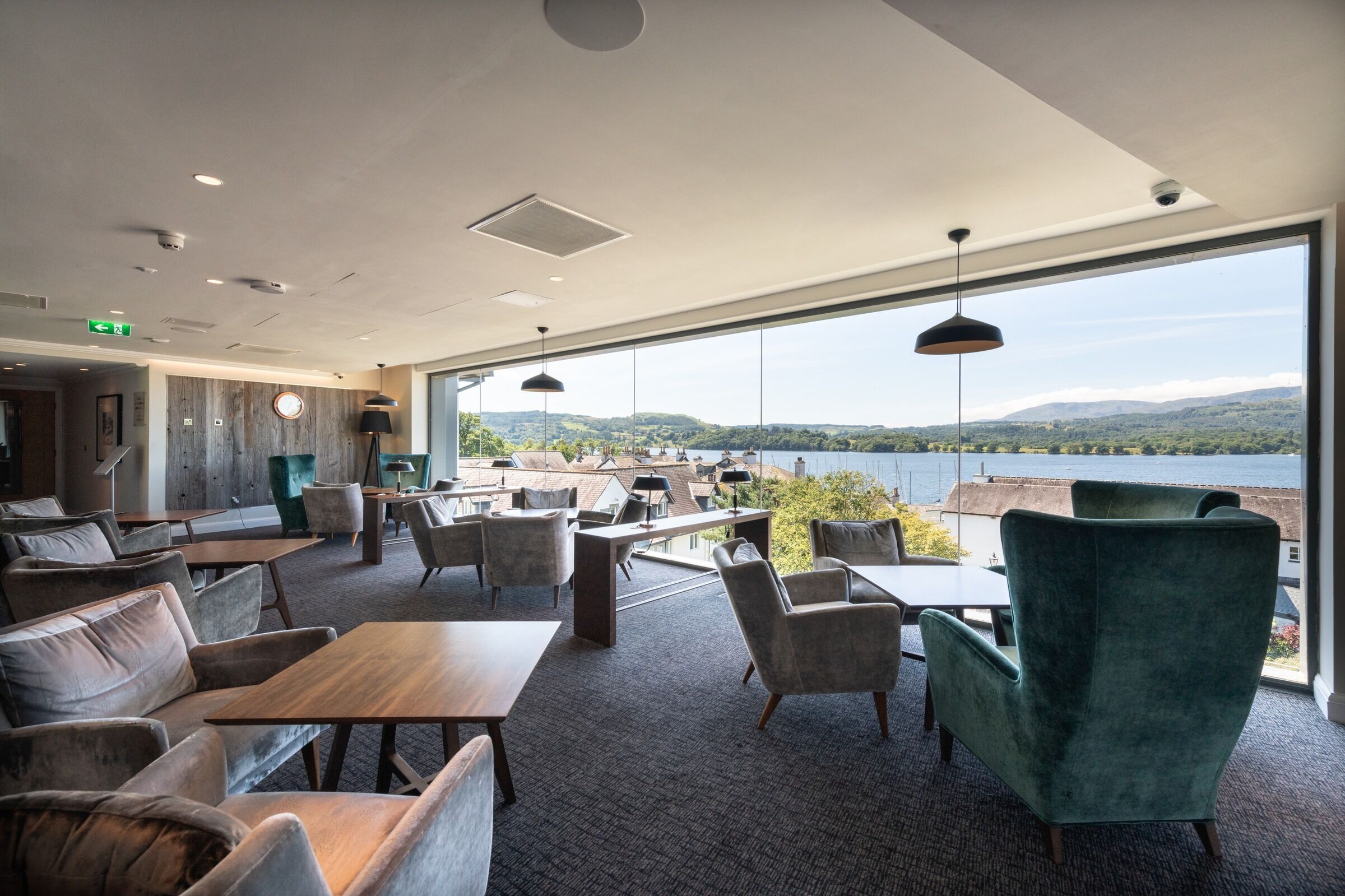 Un espacio lounge moderno con vistas a un lago y colinas.