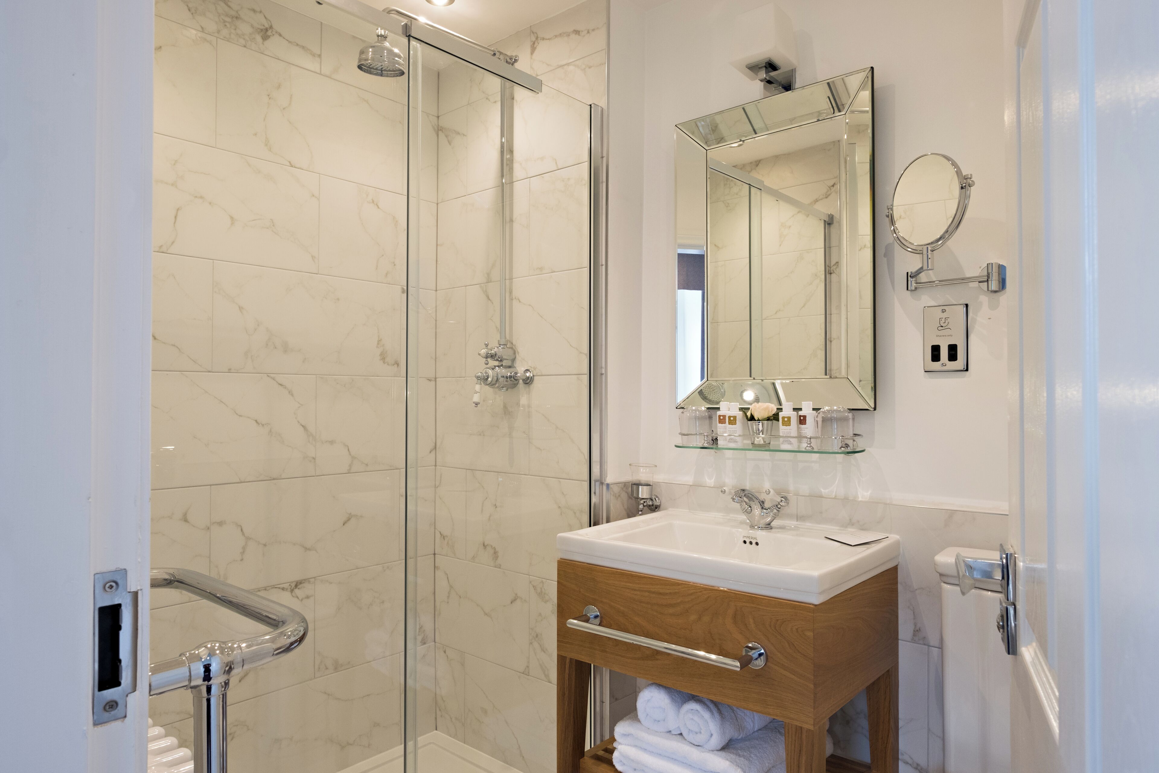 A modern bathroom with a glass shower enclosure, a wooden vanity with a sink, and a mirror above the vanity.