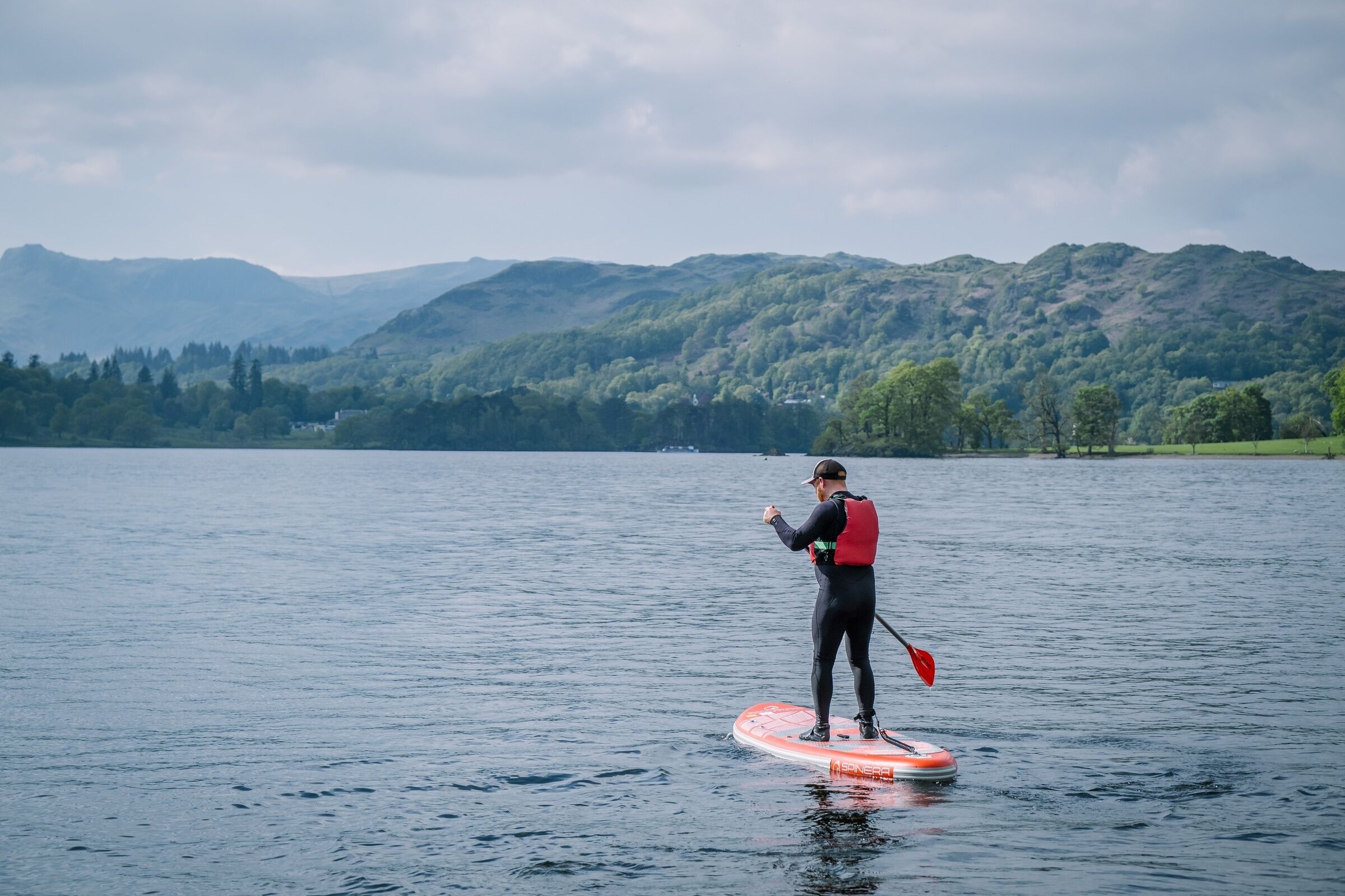 A person paddleboarding on a lake with mountains in the background.