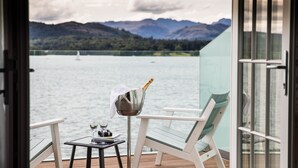 A balcony with a table, a chair, a bottle of champagne, and a glass of wine. - Low Wood Bay Resort & Spa (Windermere)