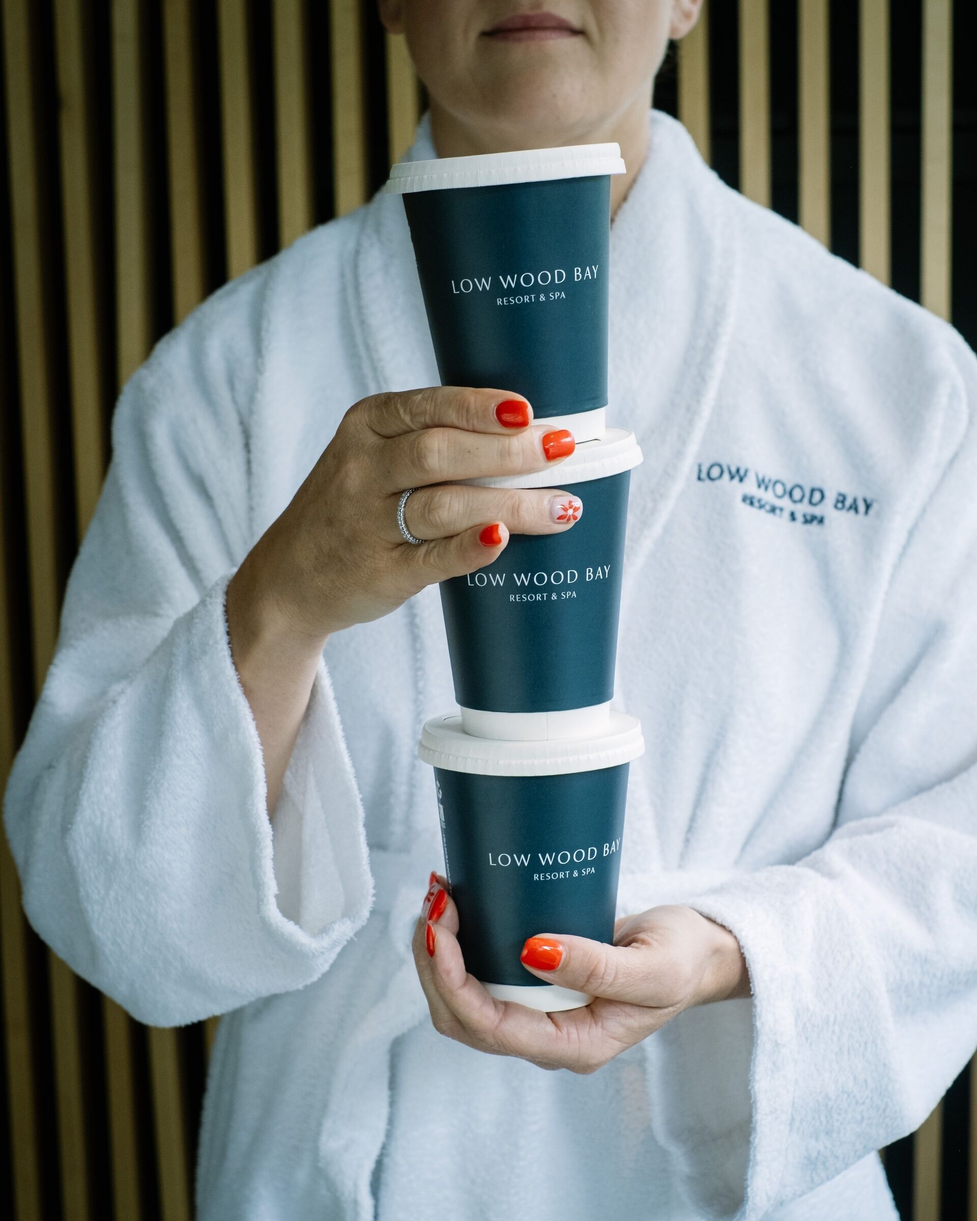 A person holding three stacked containers with 'LOW WOOD BAY RESORT & SPA' text.