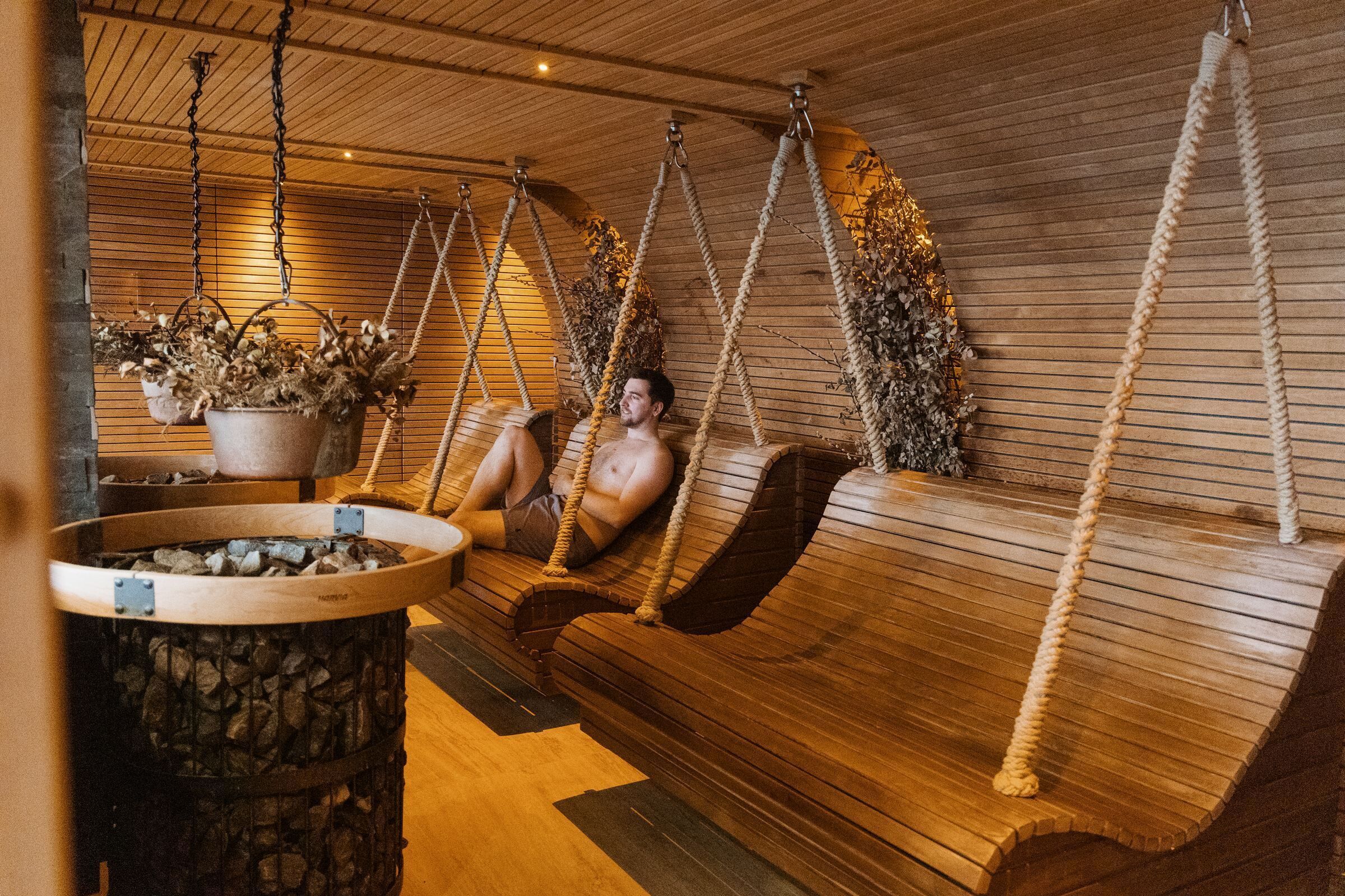 Una sauna con bancos de madera y columpios de cuerda.