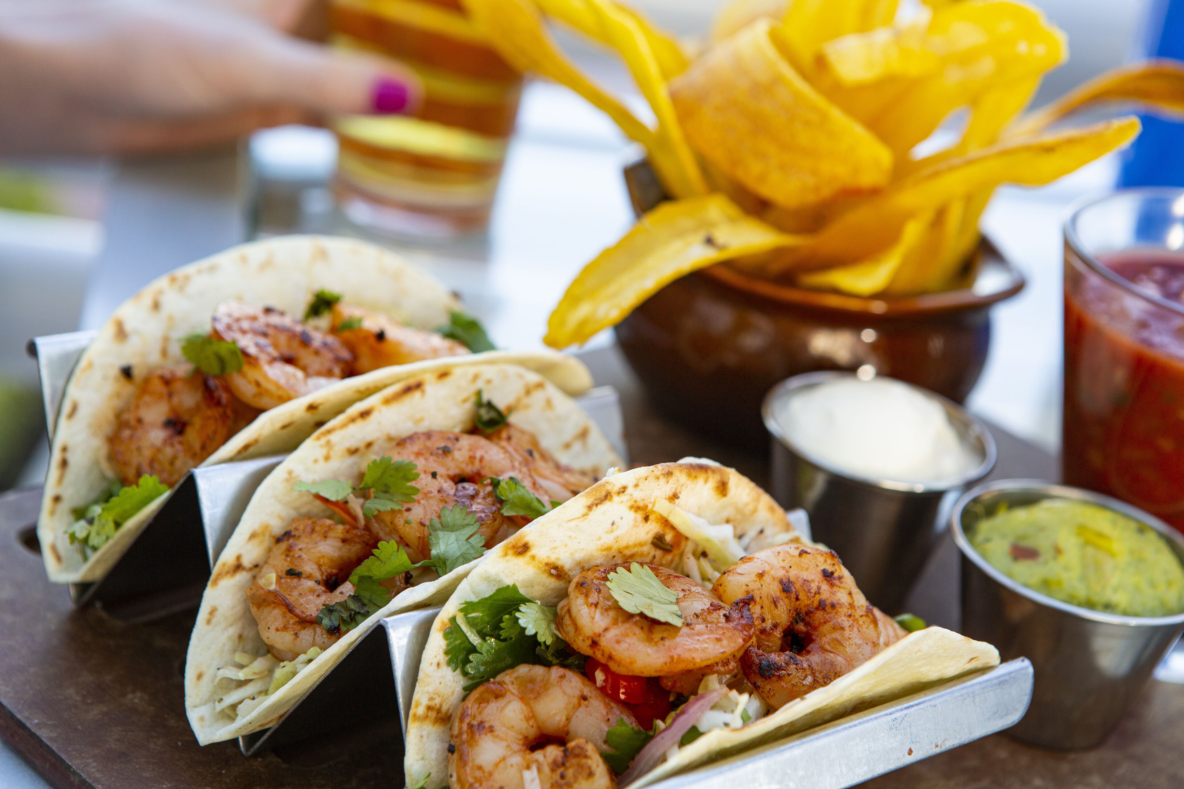 Drei Garnelen-Tacos mit Guacamole und Salsa.