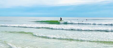 A beach with waves and a surfer.