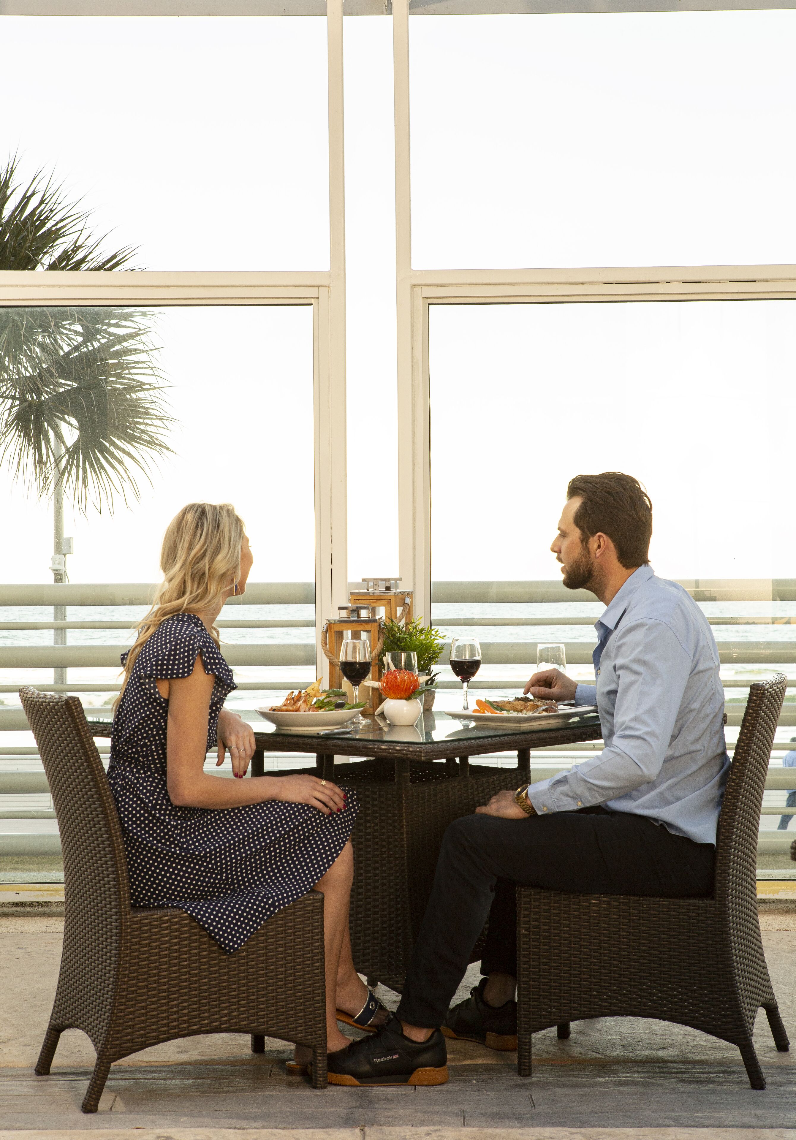 Une table à manger avec deux personnes assises, un verre de vin et une assiette de nourriture.