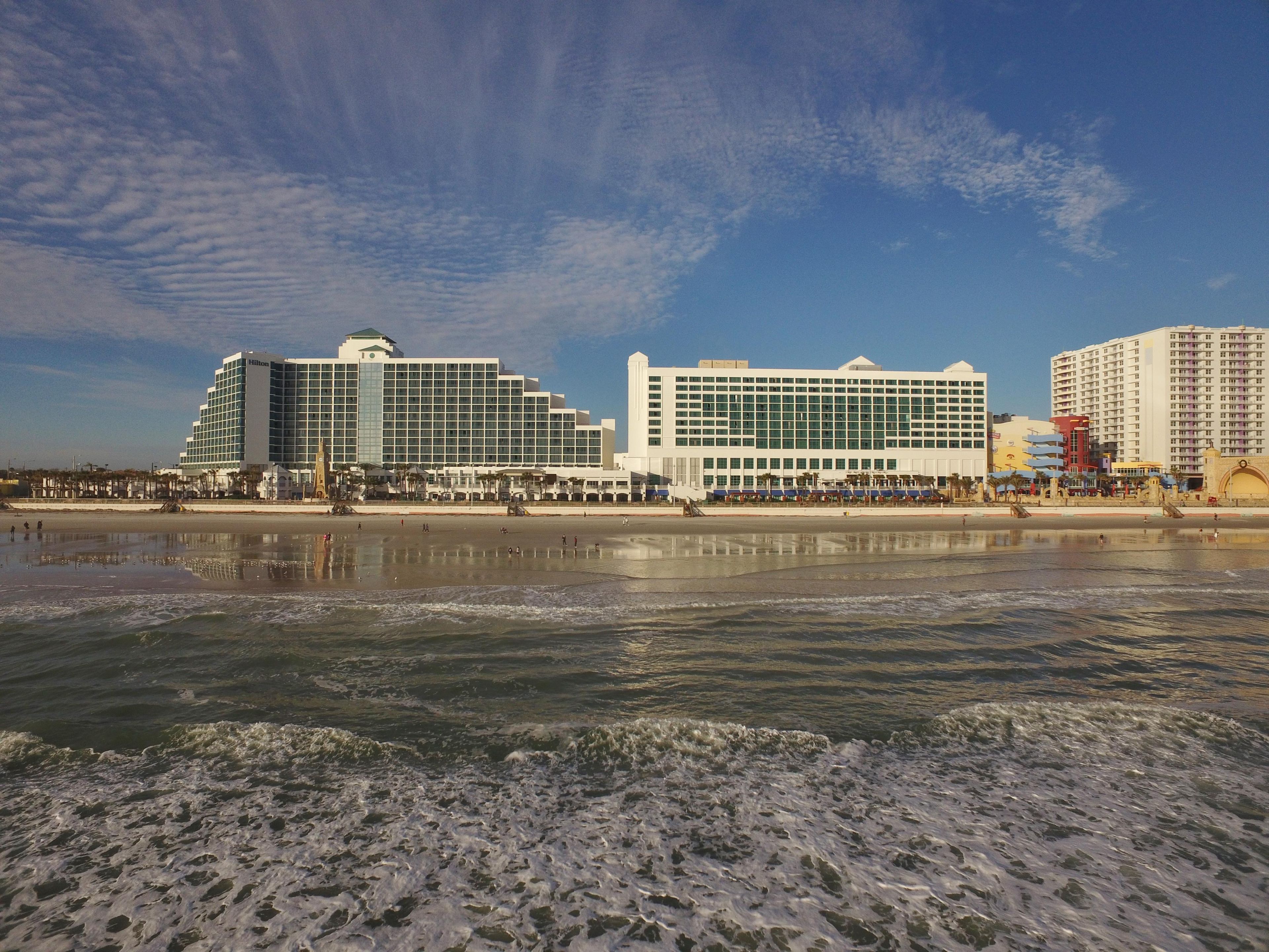 Un hôtel situé en bord de mer, composé de plusieurs bâtiments, avec une plage de sable et une mer calme.