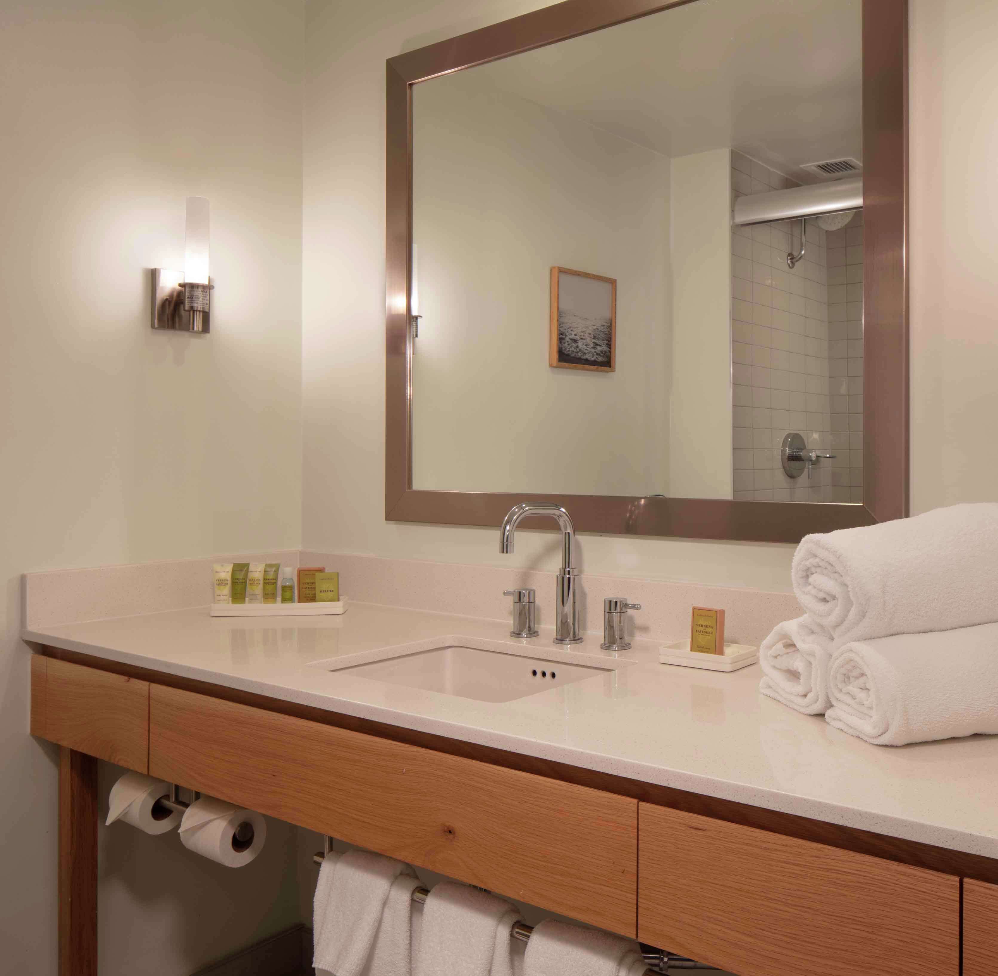 A bathroom with a large mirror, a sink with a faucet, and a towel rack.