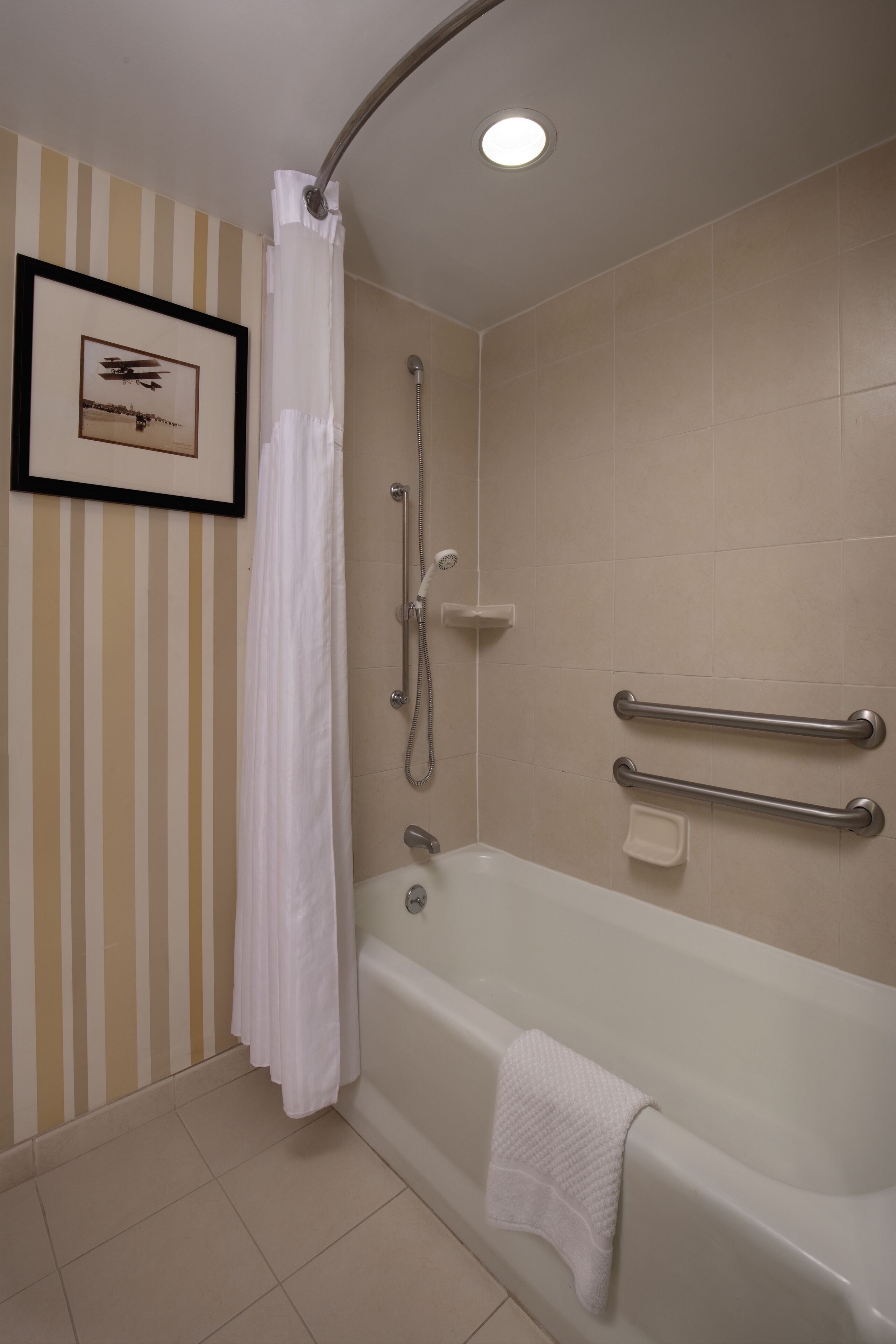 Une salle de bain équipée d’une baignoire, d’une douche et d’une barre d’appui.